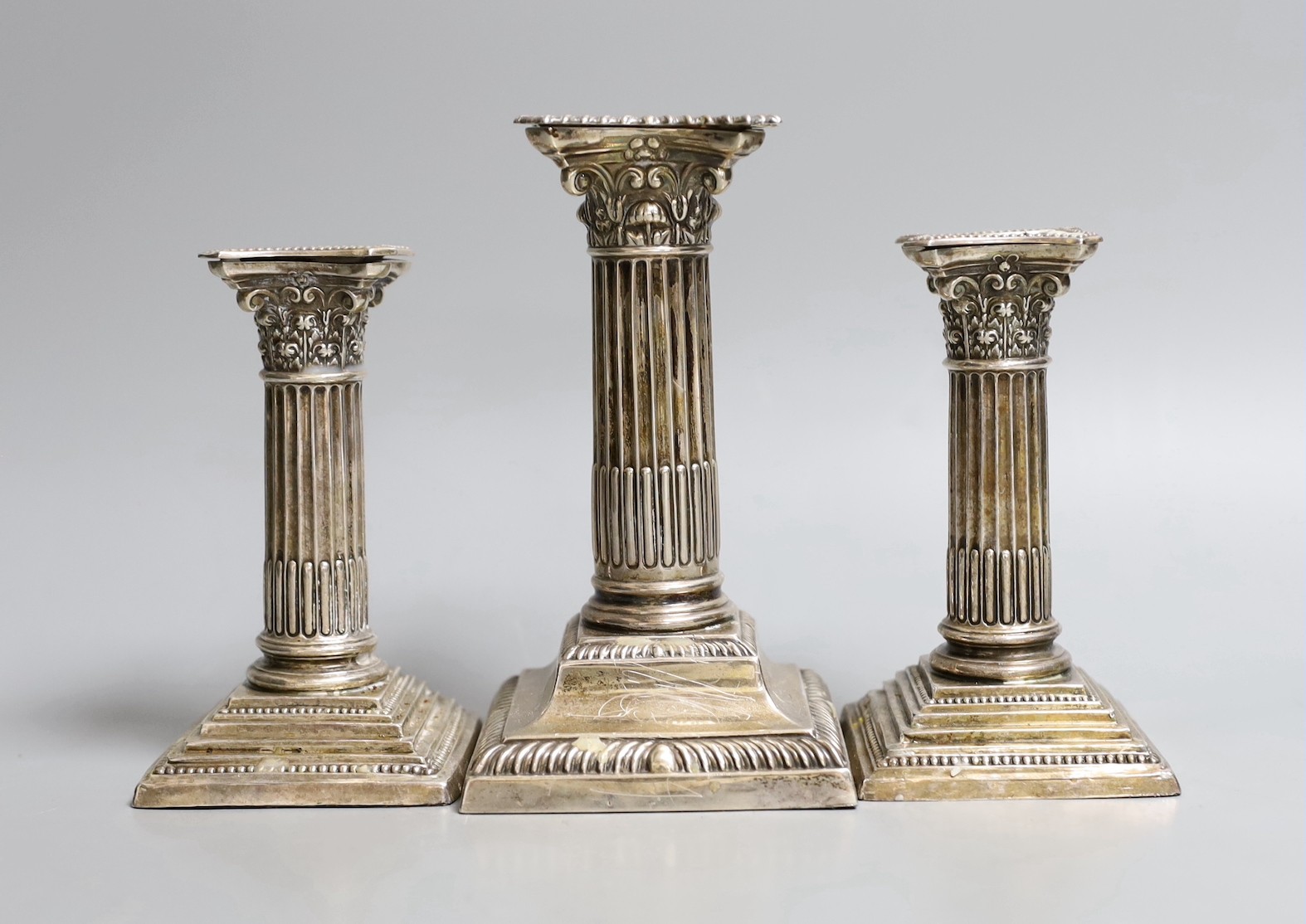 A pair of George V silver Corinthian column dwarf candlesticks, Cooper Brothers & Sons, Sheffield, 1911, 11.8cm, weighted and another similar larger candlestick.